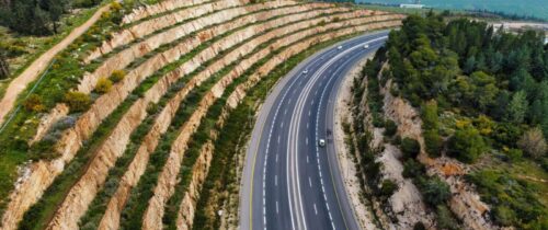 Stunning aerial view of a highway winding through terraced hills and lush greenery.