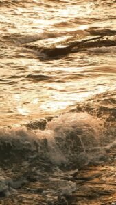 Experience the serene beauty of ocean waves illuminated by the golden hues of sunset.