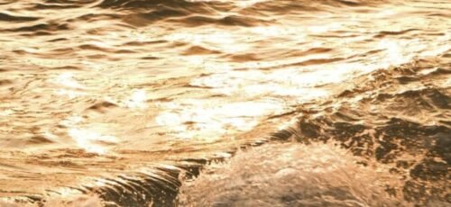 Experience the serene beauty of ocean waves illuminated by the golden hues of sunset.