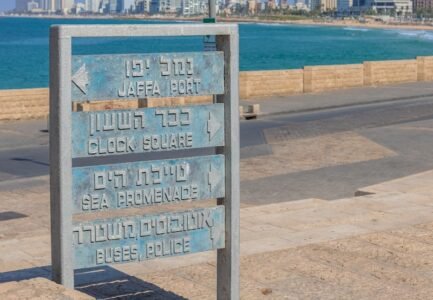 a sign in front of a body of water with a city in the background