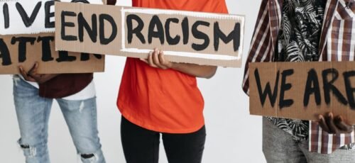 Activists holding signs with messages against racism in a peaceful protest.