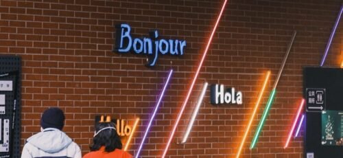 People look at neon signs with greetings in different languages